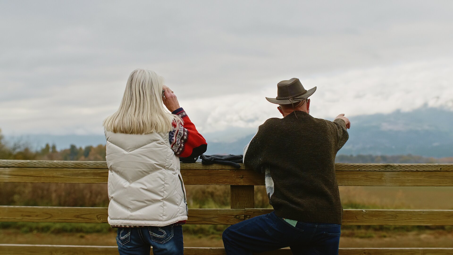 Two birdwatchers leaning on a fence overlooking the Salmon Arm foreshore on the BC Bird Trail