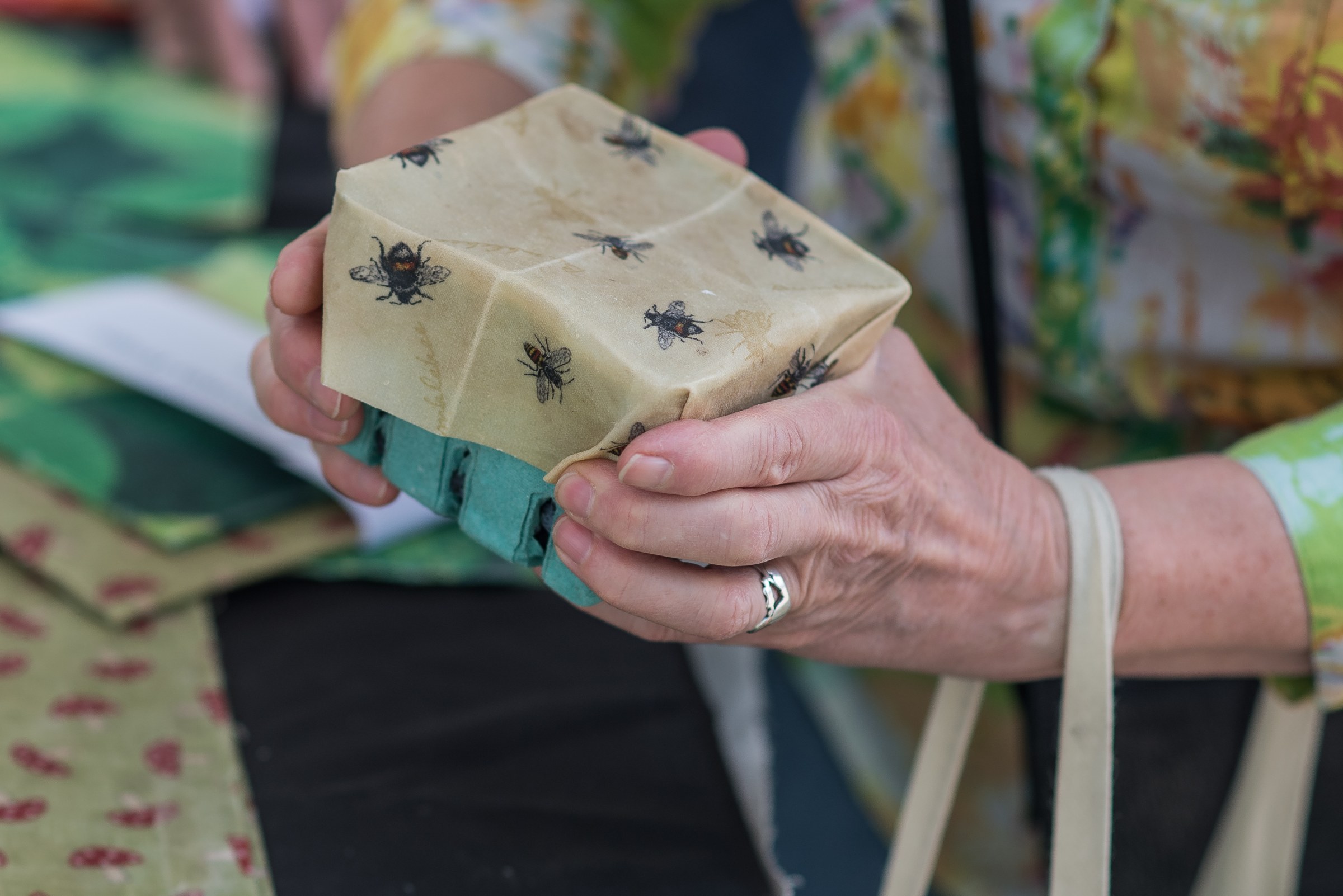 A vendor handing over fresh-baked bread wrapped in beeswax paper at the market