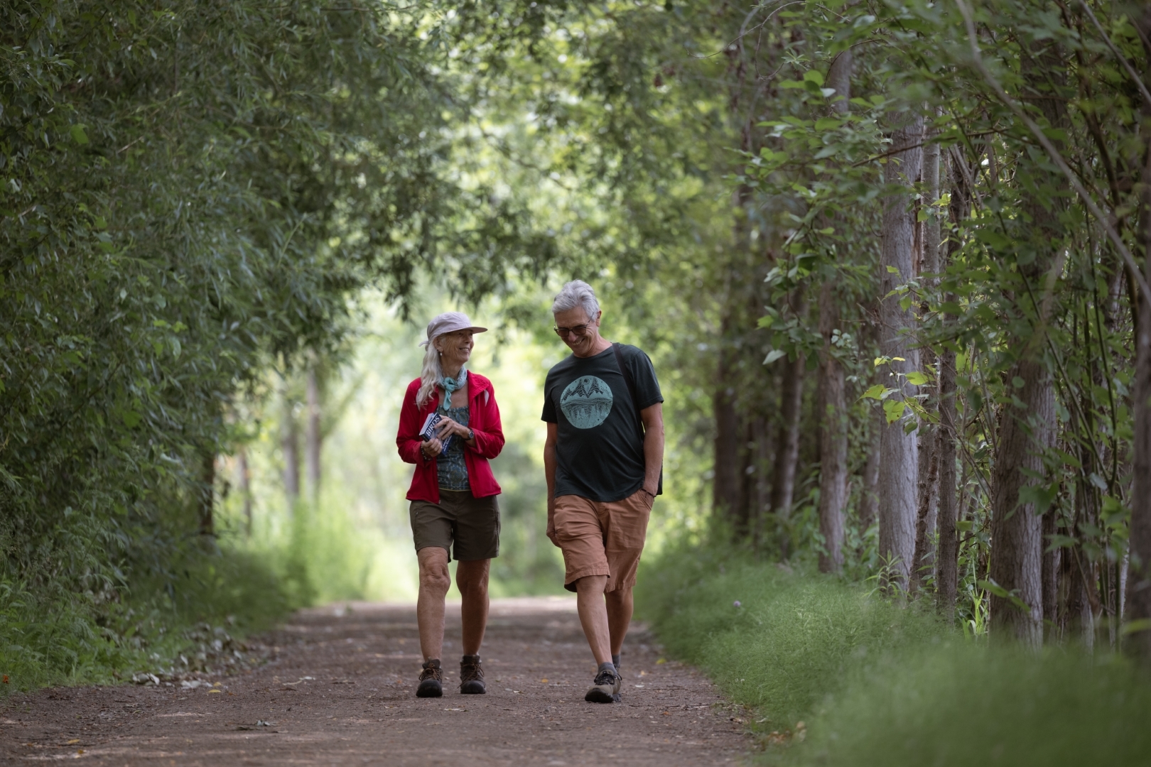 A couple walking a leafy Salmon Arm trail, sharing an easy afternoon together